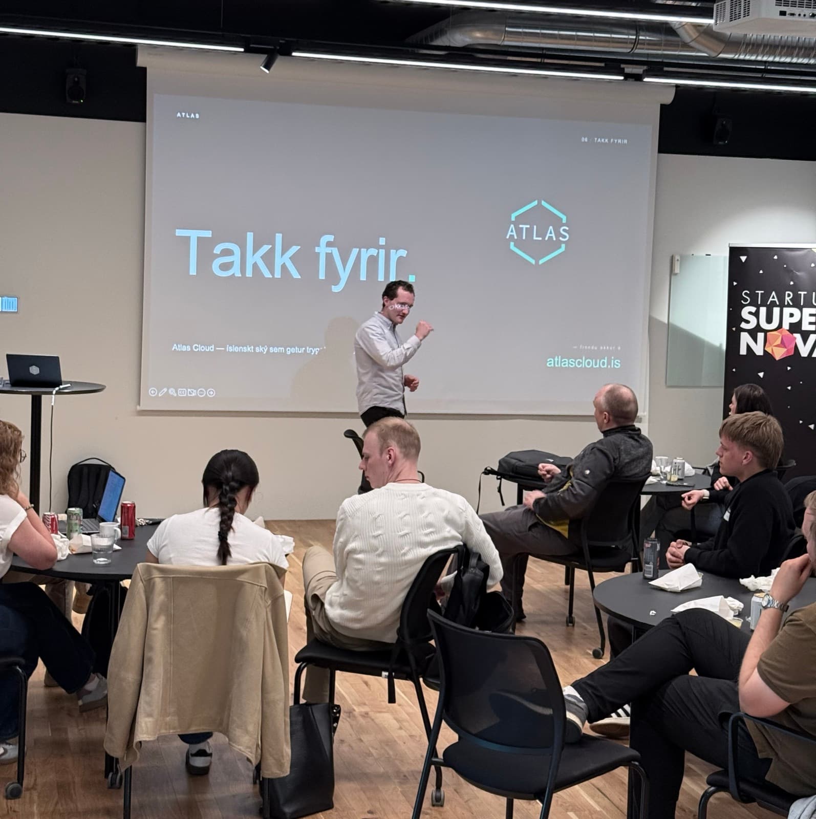 Atlas presenting at the Startup SuperNova Founder's Lunch. The slide on screen reads „Takk fyrir.“ and the audience is seated at tables in the room.